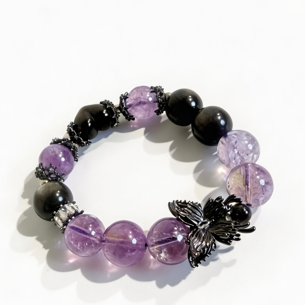 Close-up of purple amethyst beads, dark obsidian beads, and black butterfly bracelet charm
