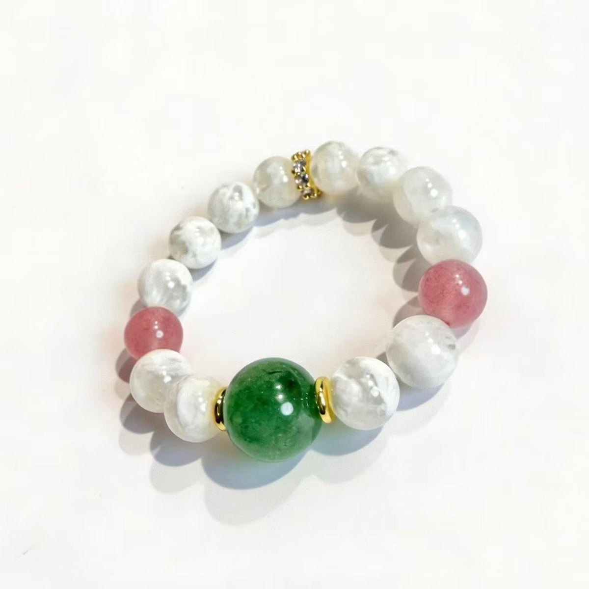 Close-up of green and pink strawberry quartz beads with milky white snow phantom quartz and gold-tone accents